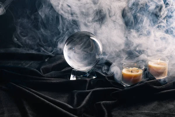 Boule de cristal et bougies avec de la fumée autour sur fond sombre — Photo de stock