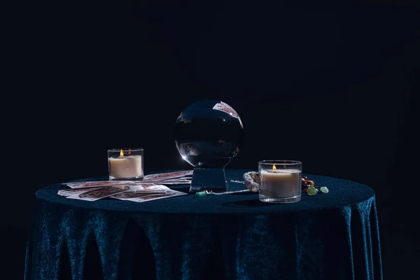 Київ, Україна - 9 січня 2020: кришталевий м'яч зі свічками, картками таро, камінням та ланцюгом на круглому столі, ізольованим на чорному. — стокове фото