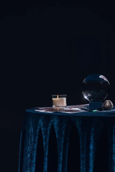 KYIV, UKRAINE - JANUARY 9, 2020: crystal ball with candle and occult objects on round table isolated on black — Stock Photo