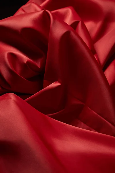 Vista de perto de pano de seda texturizado vermelho macio e amassado isolado em preto — Fotografia de Stock
