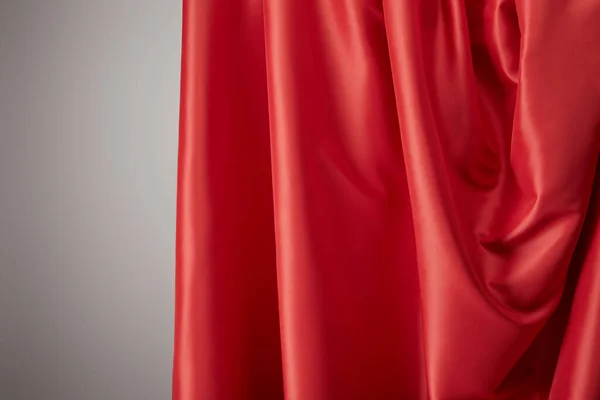 Close up view of red soft and wavy silk textured cloth on grey background — Stock Photo
