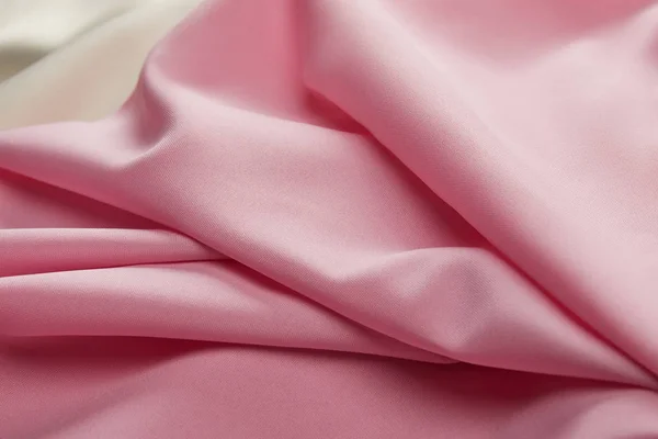 Близкий вид атласной розовой и белой мягкой и волнистой ткани — стоковое фото