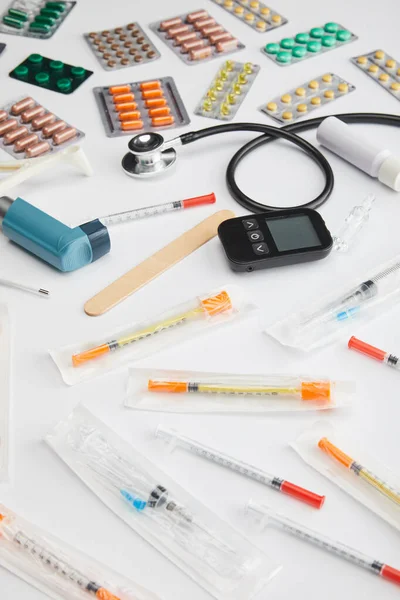 Vista de alto ângulo de medicamentos coloridos, seringas e objetos médicos em branco — Fotografia de Stock
