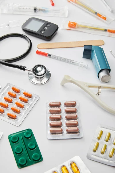 Selective focus of stethoscope, asthma inhaler and medical objects on white background — Stock Photo