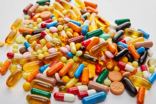 Selective focus of bright multicolored capsules and pills on white background — Stock Photo