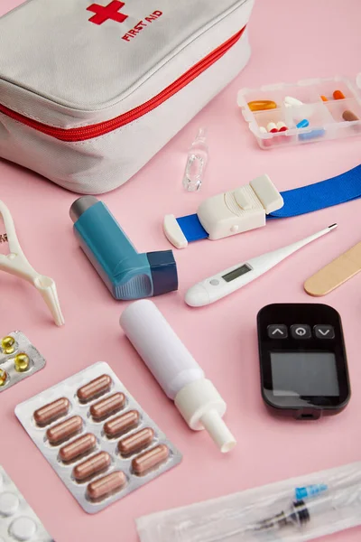 Vue grand angle de la trousse de premiers soins près des objets médicaux sur fond rose — Photo de stock