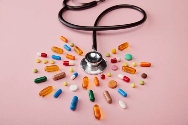 High angle view of stethoscope near bright colorful pills on pink — Stock Photo
