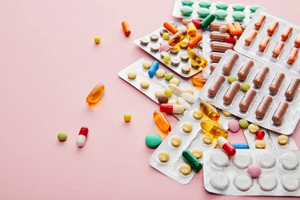 Vista de ángulo alto de las medicinas coloridas en rosa - foto de stock