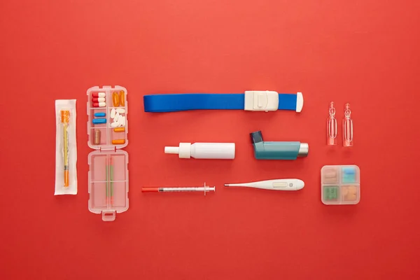 Posa piatta con medicinali e oggetti medici su sfondo rosso — Foto stock