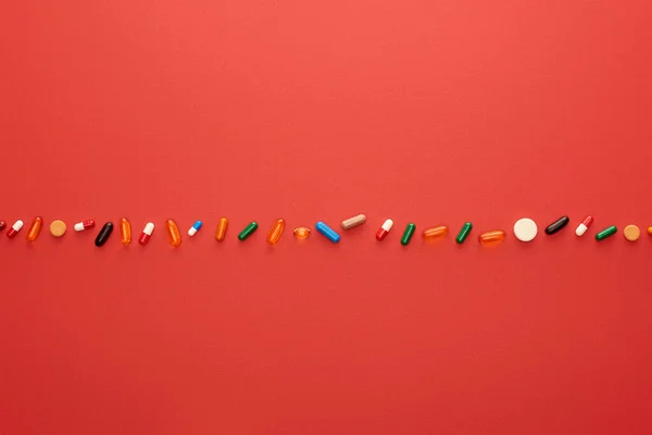 Draufsicht auf bunte helle Pillen auf rotem Hintergrund — Stockfoto