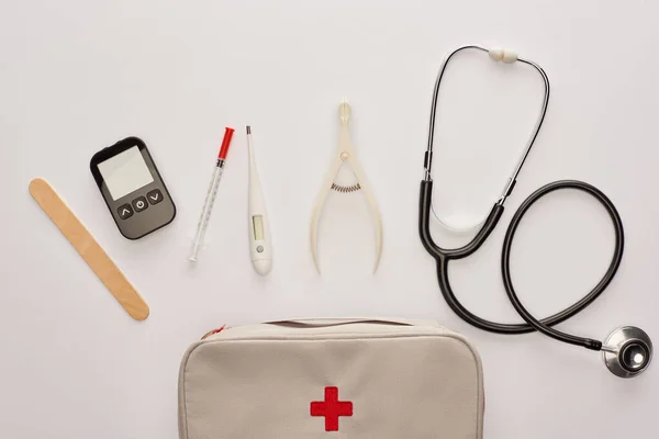 Vue du dessus de la trousse de premiers soins avec des objets médicaux sur blanc — Photo de stock