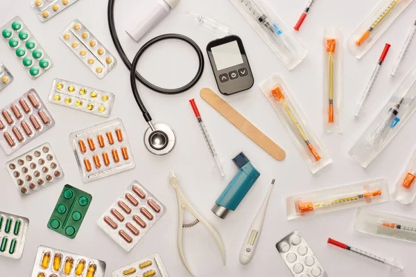 Vista superior de píldoras, jeringas y objetos médicos sobre fondo blanco - foto de stock