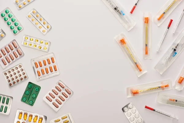 Vista dall'alto di pillole e siringhe su sfondo bianco — Foto stock