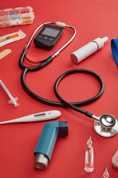 Vista en ángulo alto de objetos médicos y medicamentos en rojo - foto de stock