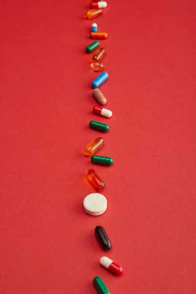 Visão de alto ângulo de pílulas brilhantes no fundo vermelho — Fotografia de Stock