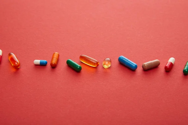 Visão de alto ângulo de pílulas no fundo vermelho — Fotografia de Stock