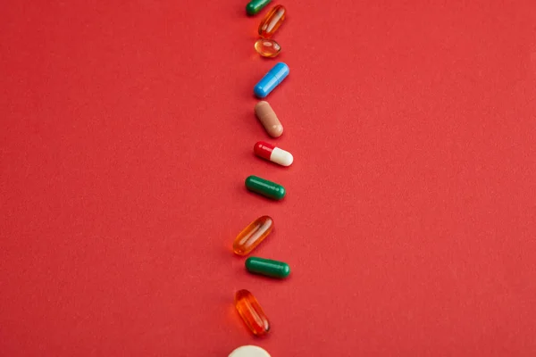 High angle view of colorful pills on red background — Stock Photo