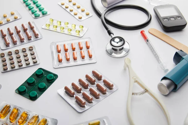 Vista de alto ángulo de objetos médicos y medicamentos sobre fondo blanco - foto de stock