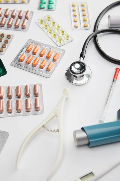 Vista de ángulo alto de los objetos médicos y píldoras sobre fondo blanco - foto de stock