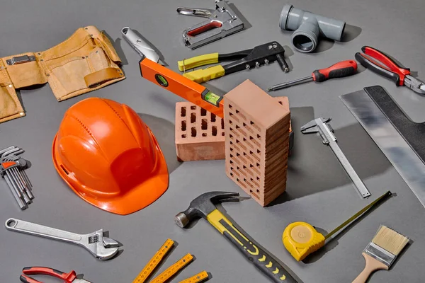 High angle view of industrial tools, bricks and helmet on grey background — Stock Photo