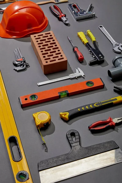 Flat lay with brick, helmet and industrial tools on grey background — Stock Photo