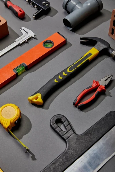 Flat lay with measuring tape, calipers, hammer, screwdriver, brush, angle keys, putty knife and spirit levels on grey background — Stock Photo