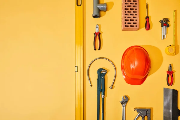 Flache Verlegung mit Industriewerkzeug, Maßband und Helm, auf gelbem Hintergrund — Stockfoto