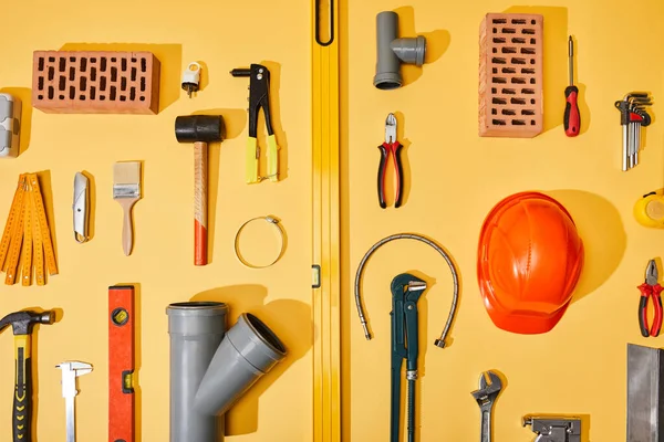 Flat lay with industrial tools, bricks and helmet on yellow background — Stock Photo