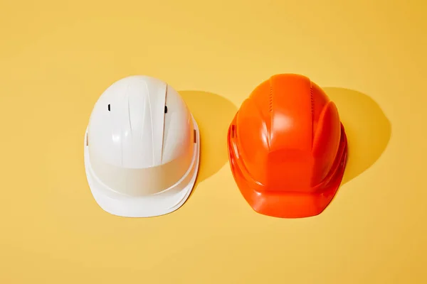 Top view of orange and white helmets on yellow background — Stock Photo