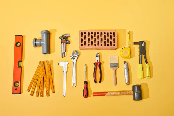 Draufsicht auf Industriewerkzeuge und Ziegel auf gelbem Hintergrund — Stockfoto