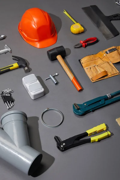 Flat lay com capacete, cinto de ferramentas e ferramentas industriais em fundo cinza — Fotografia de Stock
