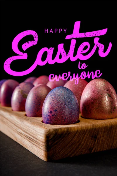 Selective focus of Easter eggs on wooden board on black with happy Easter to everyone illustration — Stock Photo