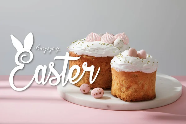 Leckere Osterkuchen und Wachteleier auf rundem Brett auf grau und rosa mit frohen Osterbildern — Stockfoto