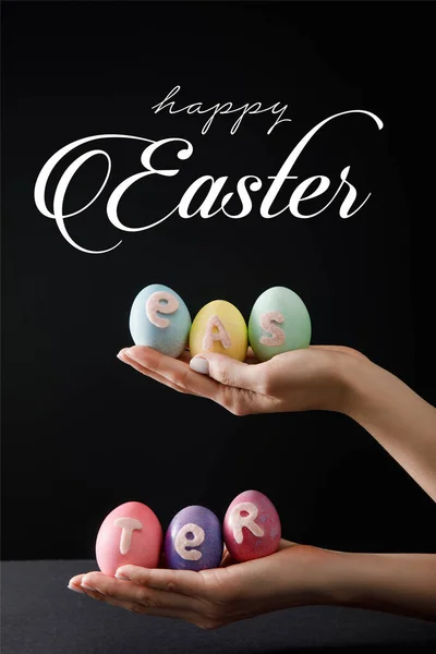 Selective focus of Easter eggs on wooden board on black with happy Easter illustration — Stock Photo