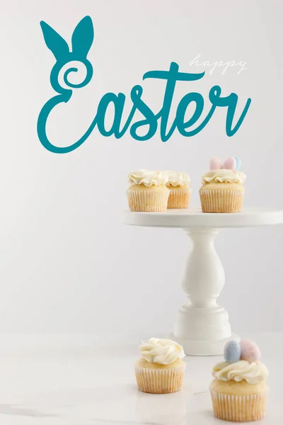 Selektive Fokussierung von Cupcakes auf Kuchenständer isoliert auf grau mit frohen Ostern Illustration — Stock Photo