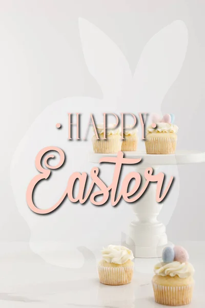 Selektive Fokussierung von Cupcakes auf Kuchenständer isoliert auf grau mit frohen Ostern Illustration — Stockfoto