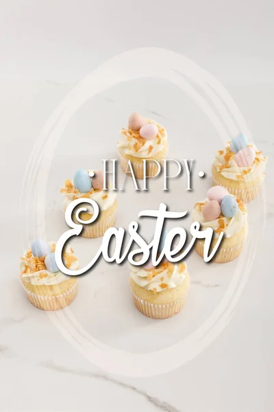 Смачні великодні кекси з розфарбованими перепелиними яйцями зверху на білому тлі з щасливою великодньою ілюстрацією — стокове фото