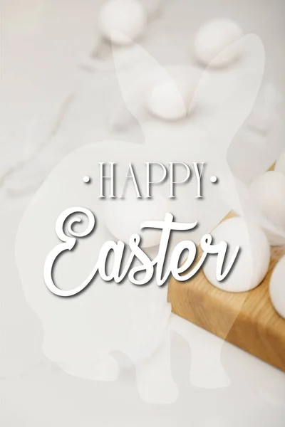 Foco seletivo de ovos na bandeja de ovos de madeira e penas no fundo branco com feliz ilustração da Páscoa — Fotografia de Stock