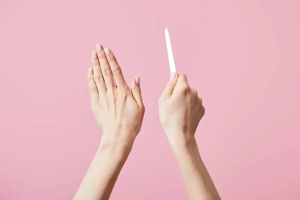 Vue recadrée des mains femelles avec lime à ongles isolée sur rose — Photo de stock