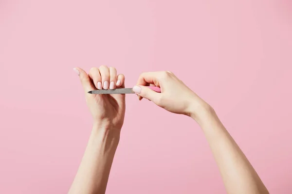 Cropped view of woman filing nails with nail file isolated on pink — Stock Photo