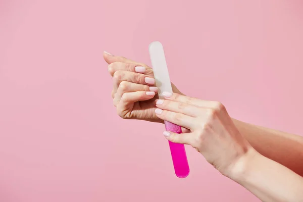 Vue partielle de la femme faisant manucure avec lime à ongles isolée sur rose — Photo de stock