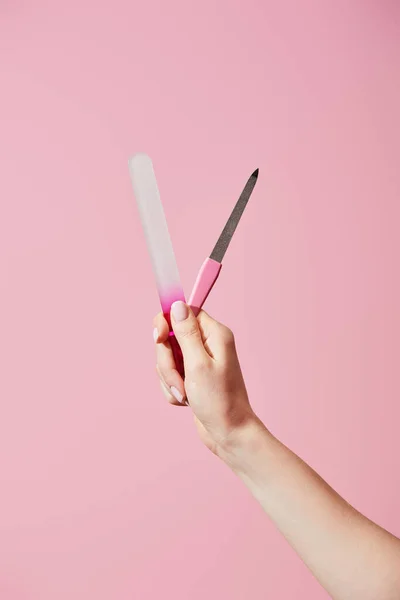 Vista recortada de la mujer sosteniendo limas de uñas aisladas en rosa - foto de stock