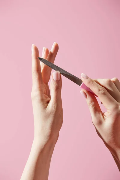 Partial view of woman filing nail isolated on pink — Stock Photo
