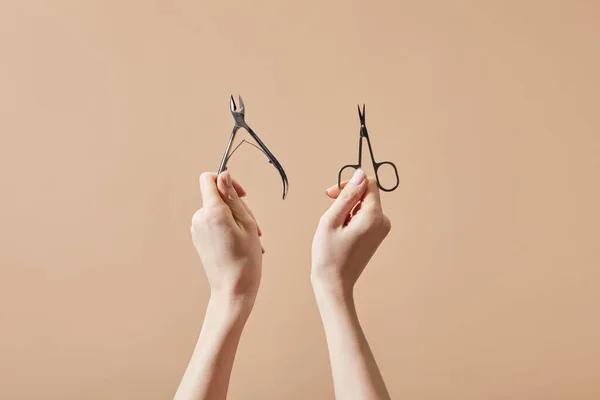 Ausgeschnittene Ansicht einer Frau mit Nagelzange und Nagelschere isoliert auf beige — Stockfoto
