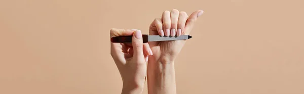 Vista cortada de mulher arquivando unhas isoladas em bege, tiro panorâmico — Fotografia de Stock