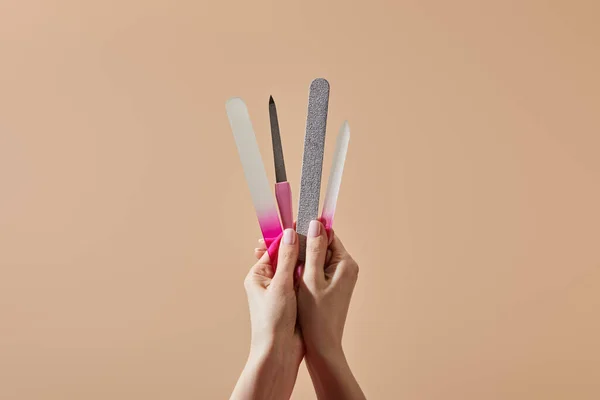 Cropped view of woman holding nail files and emery board isolated on beige — Stock Photo