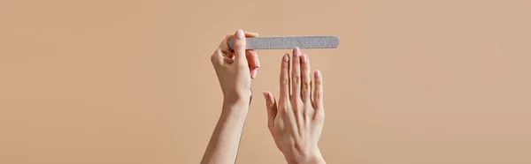 Cropped view of woman filing nail with emery board isolated on beige, panoramic shot — Stock Photo