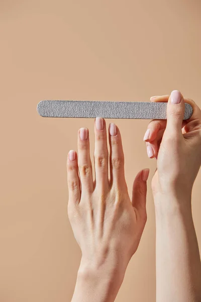 Vue recadrée de la femme classant ongle avec plateau emery isolé sur beige — Photo de stock