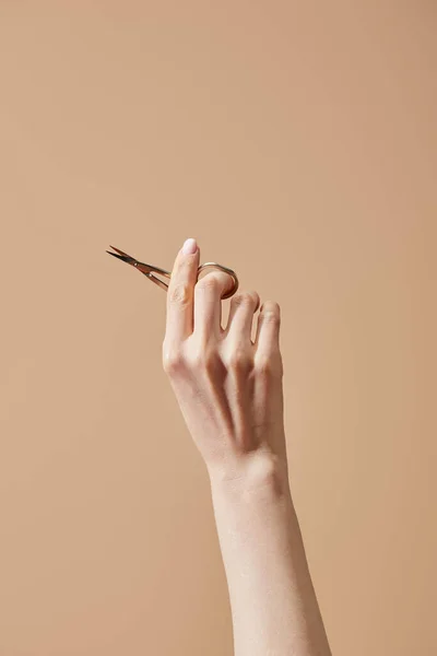 Cropped view of female hand with nail scissors isolated on beige — Stock Photo