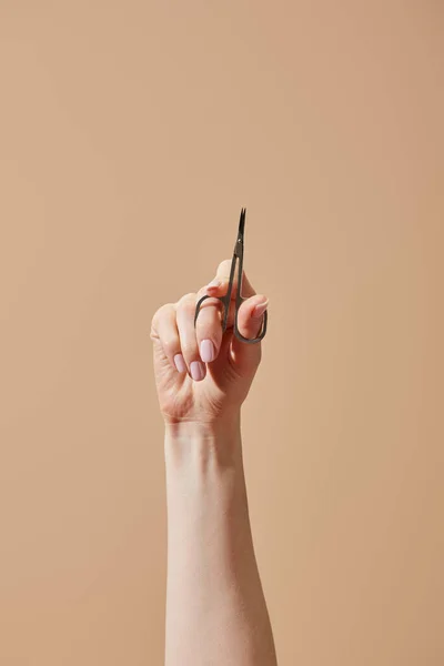 Vista parziale della mano femminile con forbici isolate su beige — Foto stock